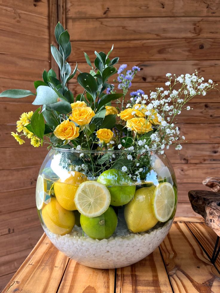Centro de mesa de estilo mediterráneo con limones, flores frescas y piedra decorativa blanca. Una composición luminosa y natural que aporta color, frescura y elegancia a cualquier espacio durante el verano.